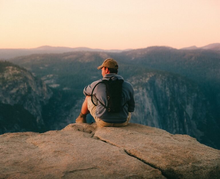 man-in-black-t-shirt-and-brown-hat-sitting-on-rock