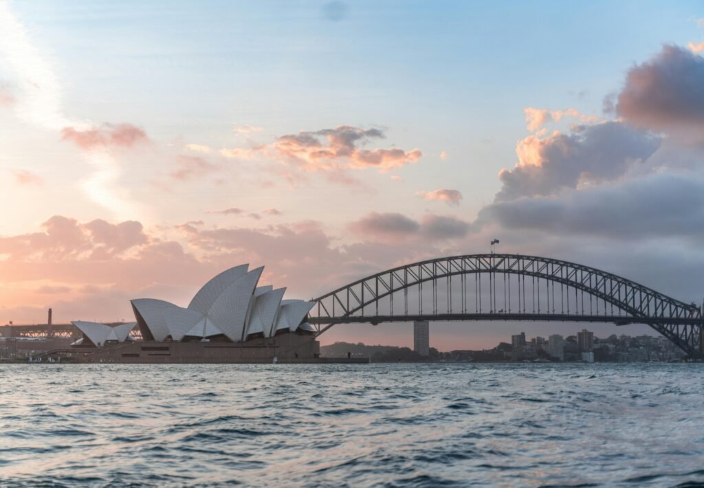 Stylish modern building and arch bridge crossing harbor against cloudy sundown sky